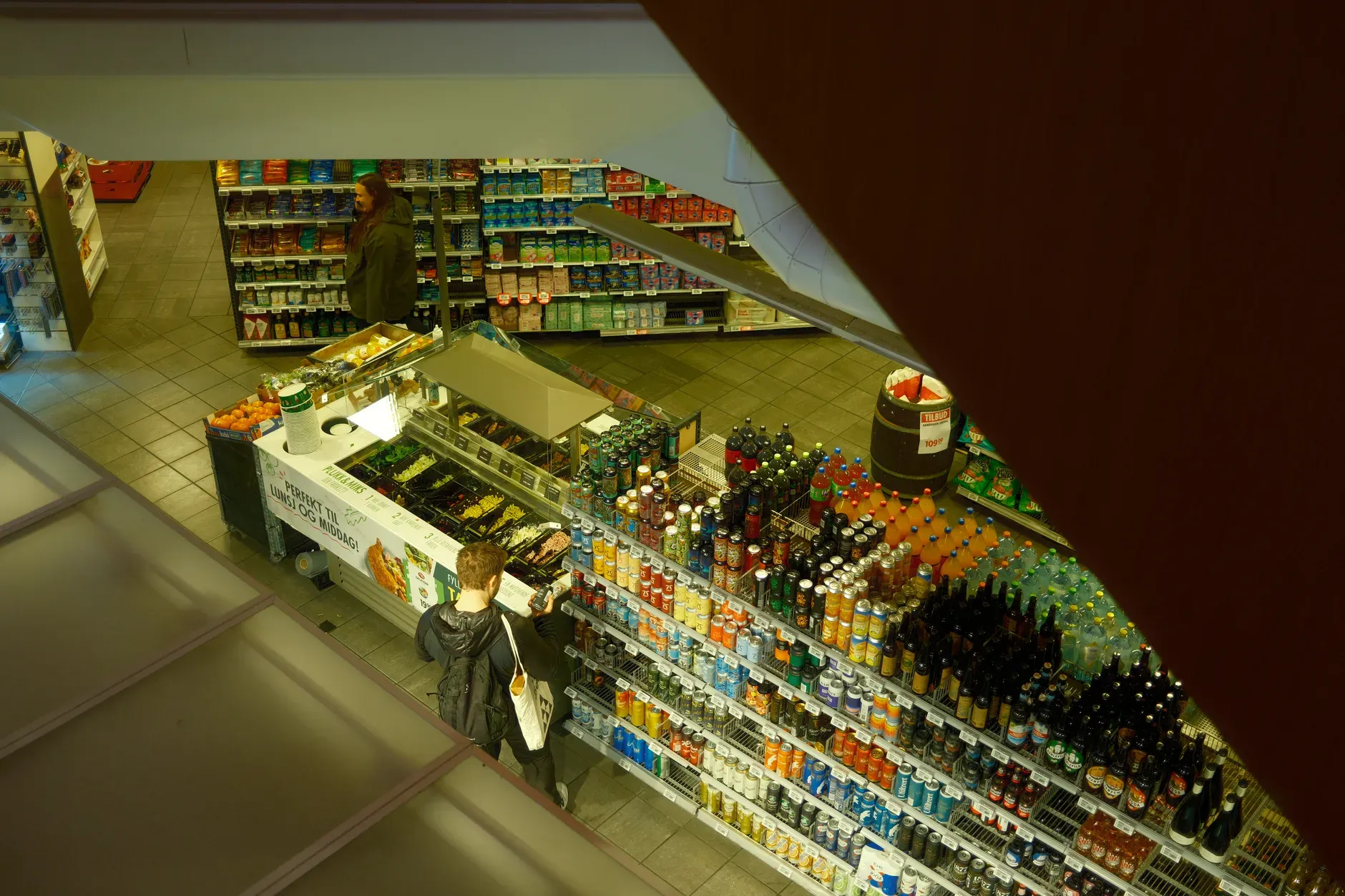 Dua'a Al-Amad Vista dall'alto di un supermercato, che mostra i clienti mentre curiosano nel reparto bevande.