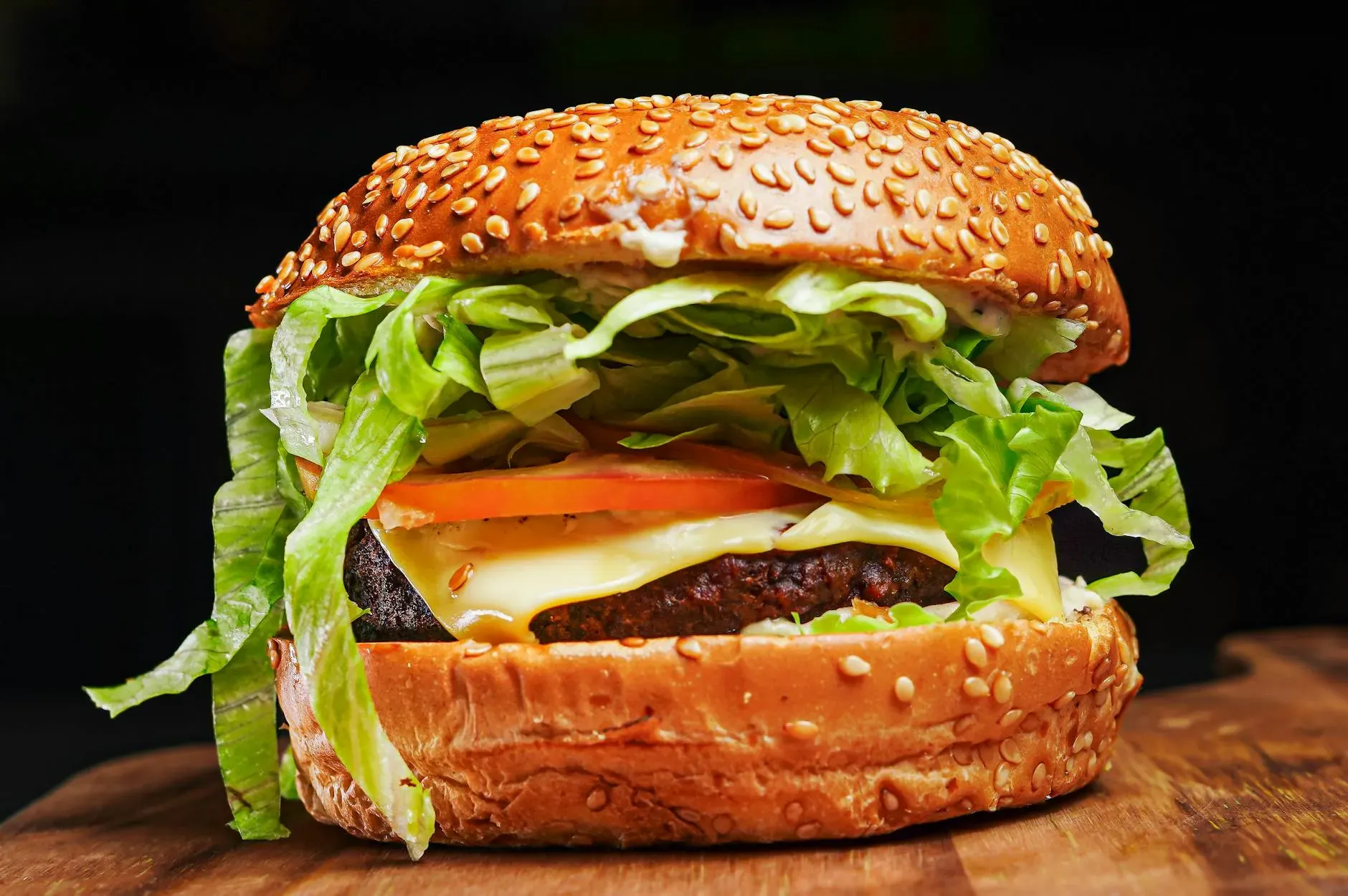 Appetitoso primo piano di un cheeseburger con lattuga, pomodoro e panino al sesamo.